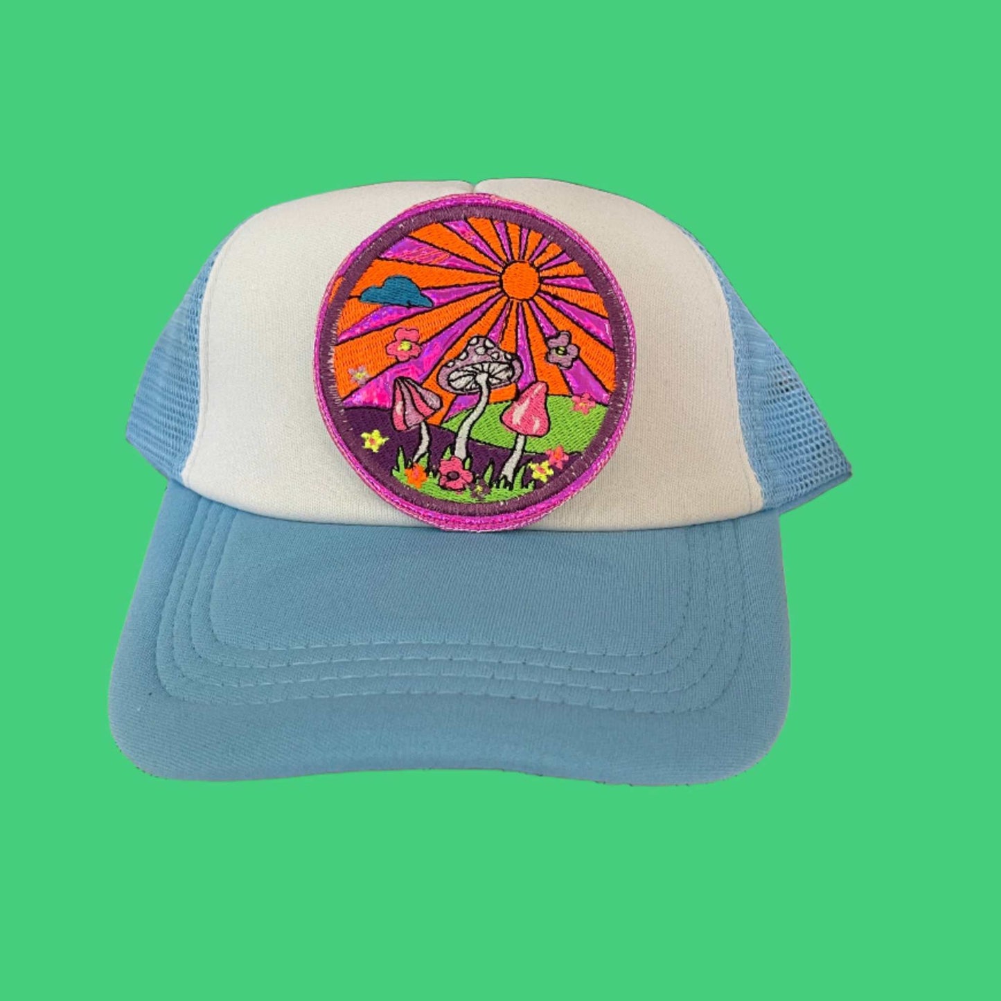 Iron-on patch featuring a vibrant sunset scene with neon pink, orange, and green mushrooms on a purple holographic background, with a sun, clouds, flowers, and landscape, outlined in neon pink.
