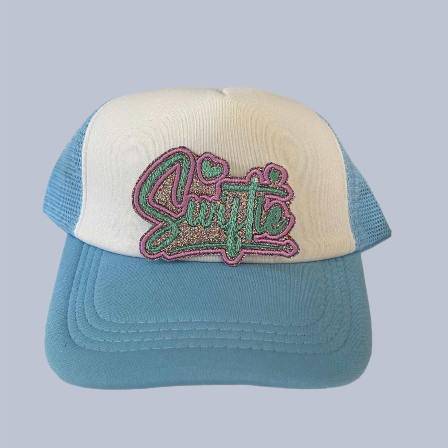 Handmade iron-on patch featuring the word "Swiftie" in glittery pastel colors with heart accents, perfect for adding to clothing, bags, or hats.