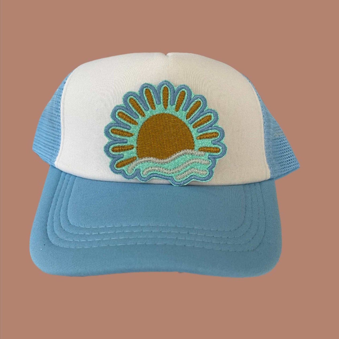 Iron-on patch featuring a copper metallic sun setting over turquoise waves, outlined in a soft teal border.