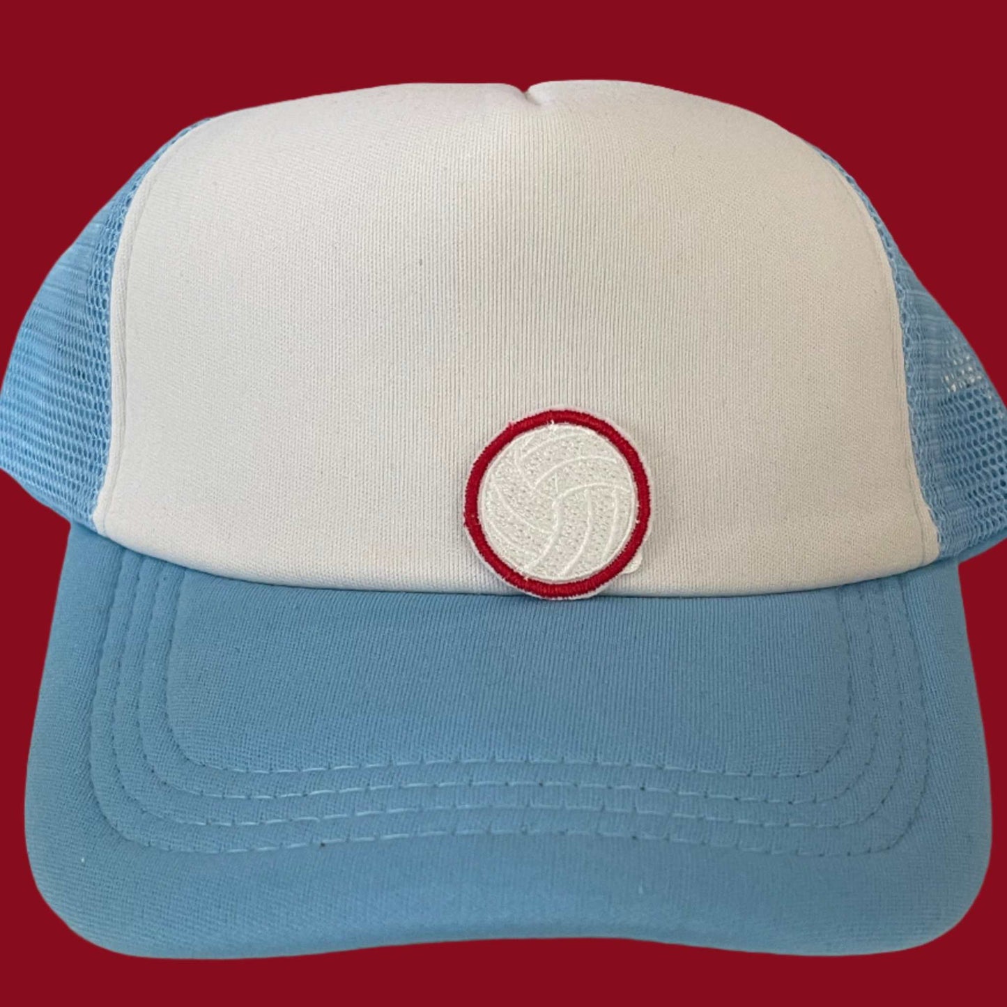 Close-up of a volleyball embroidered patch with white and red detailing, perfect for customizing hats and other accessories.