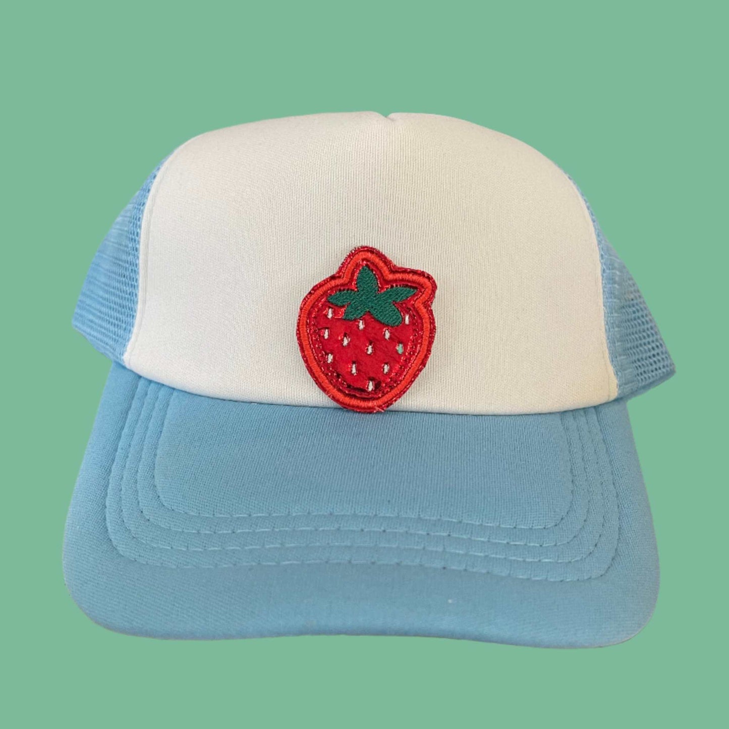 Close-up of a vibrant embroidered strawberry patch on a hat.