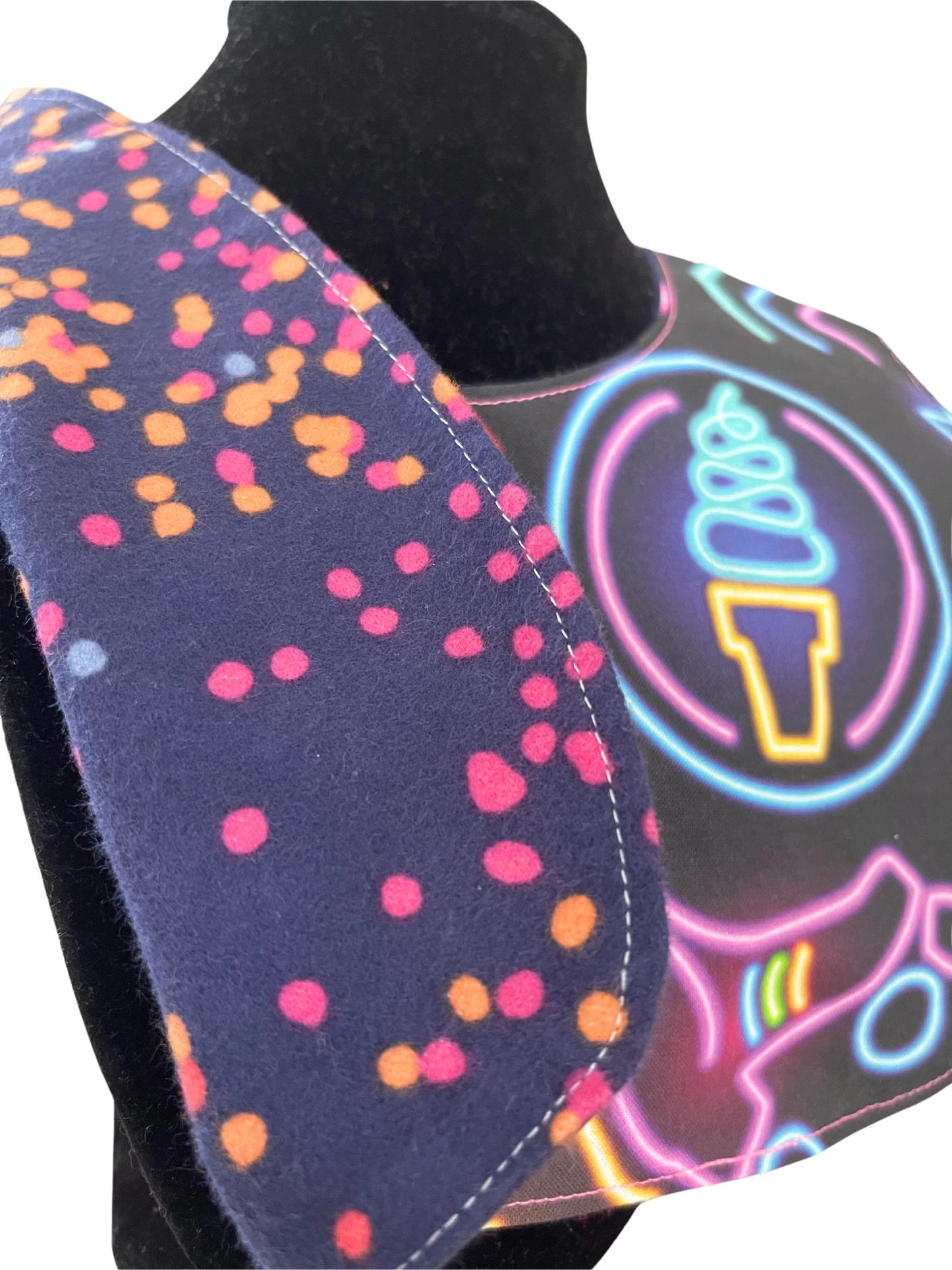 Reversible bib with neon pattern on the front, featuring hearts, stars, and ice cream cone designs.