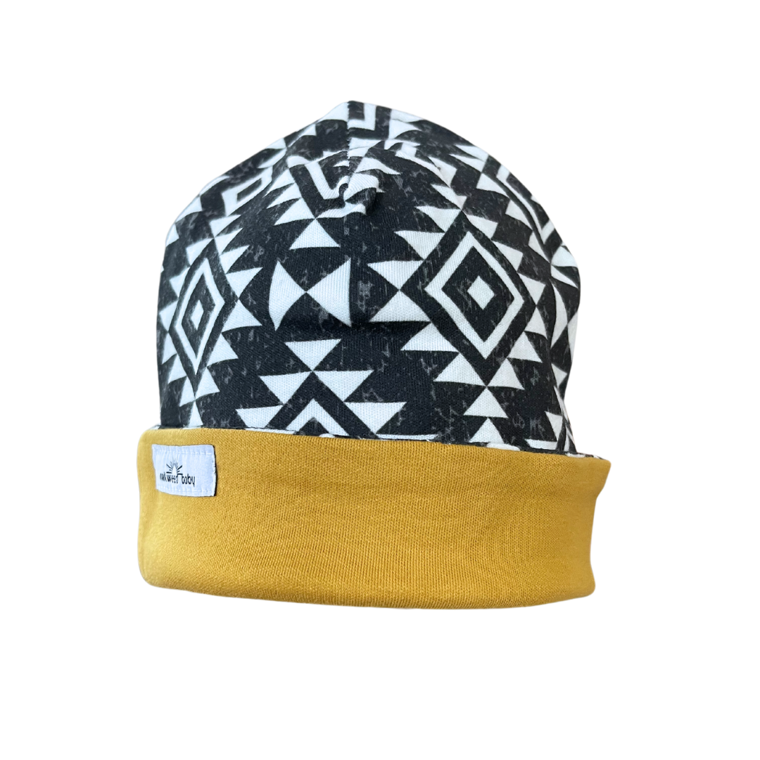 Handmade reversible organic cotton baby beanie with black and white geometric pattern and mustard trim.