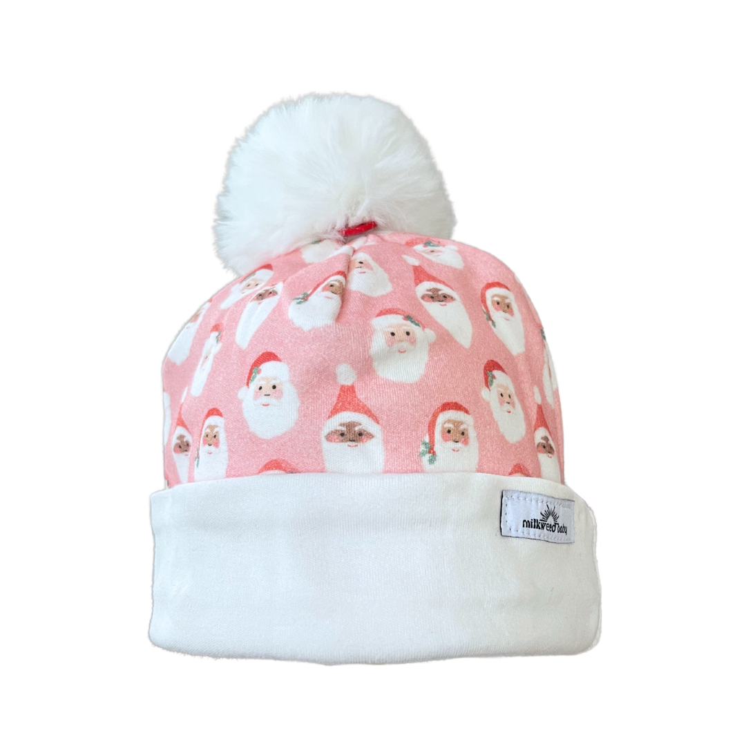Santa Baby Beanie with pink fabric, Santa face pattern, white fold-over brim, and faux fur pom pom.