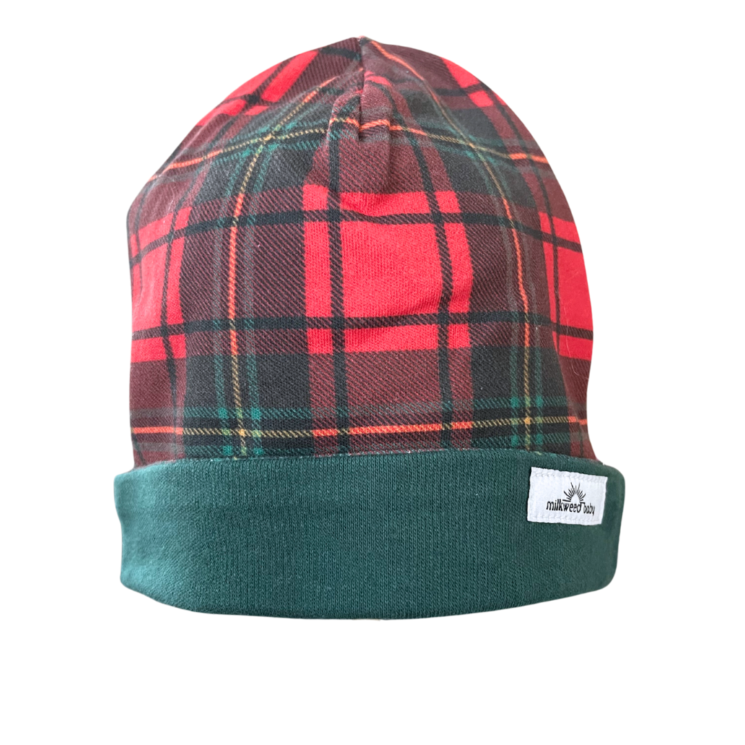 Handcrafted reversible organic cotton baby beanie with red plaid and forest green trim.