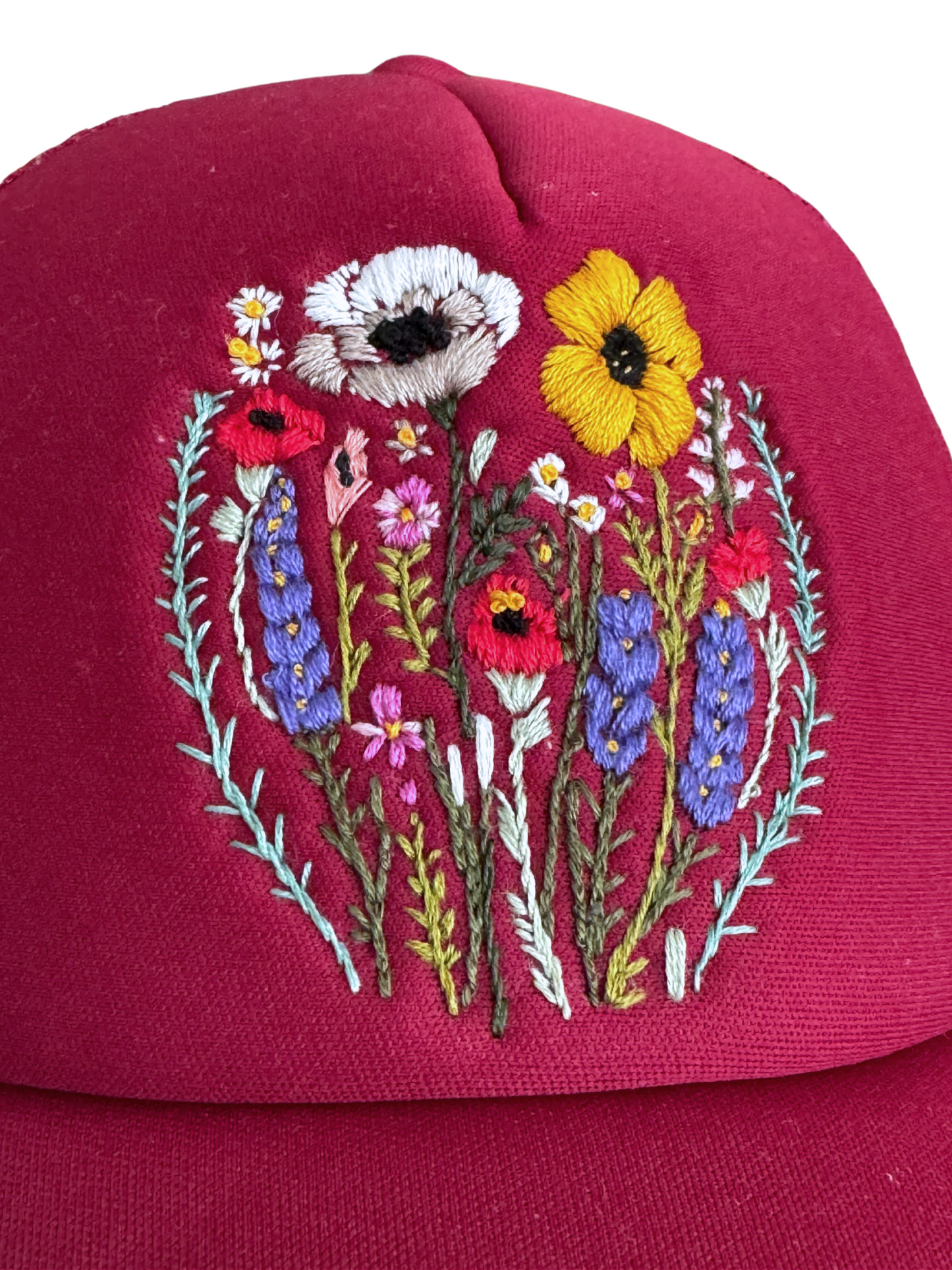 Hand-embroidered wildflower design on a red trucker hat with a detailed floral pattern.