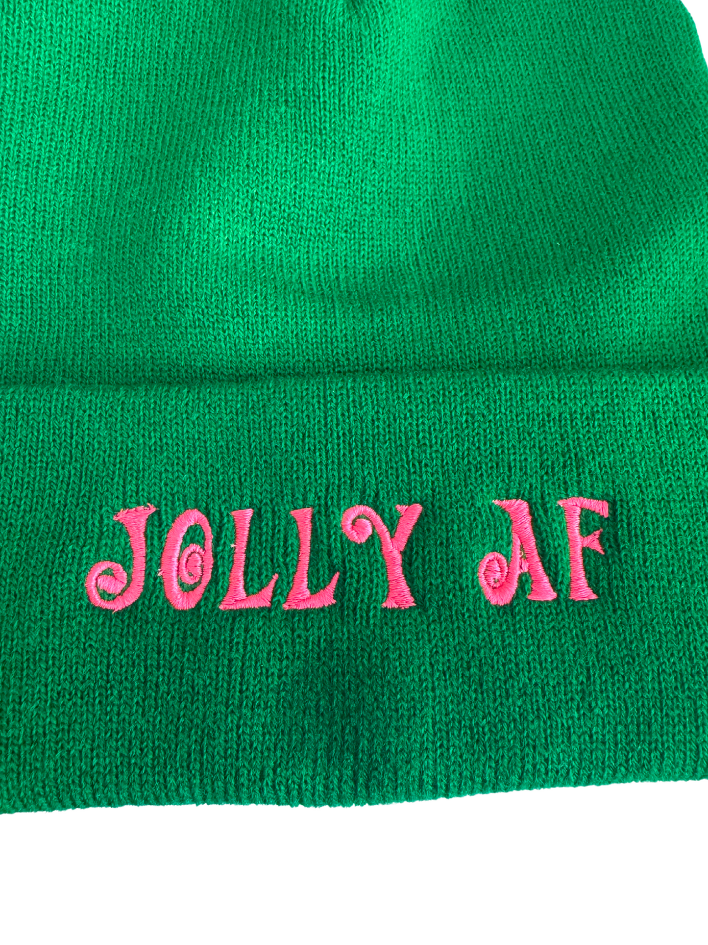 Green beanie with pink "Jolly AF" embroidery in swirled lettering, displayed on a mannequin head.