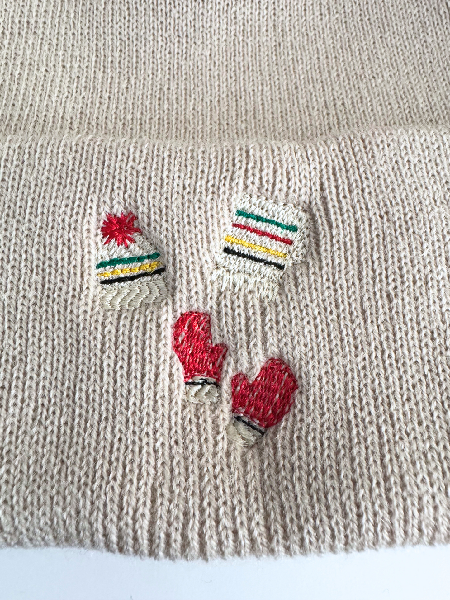 Beige winter beanie with embroidered Pendleton Glacier-inspired designs, including striped hats and red mittens.