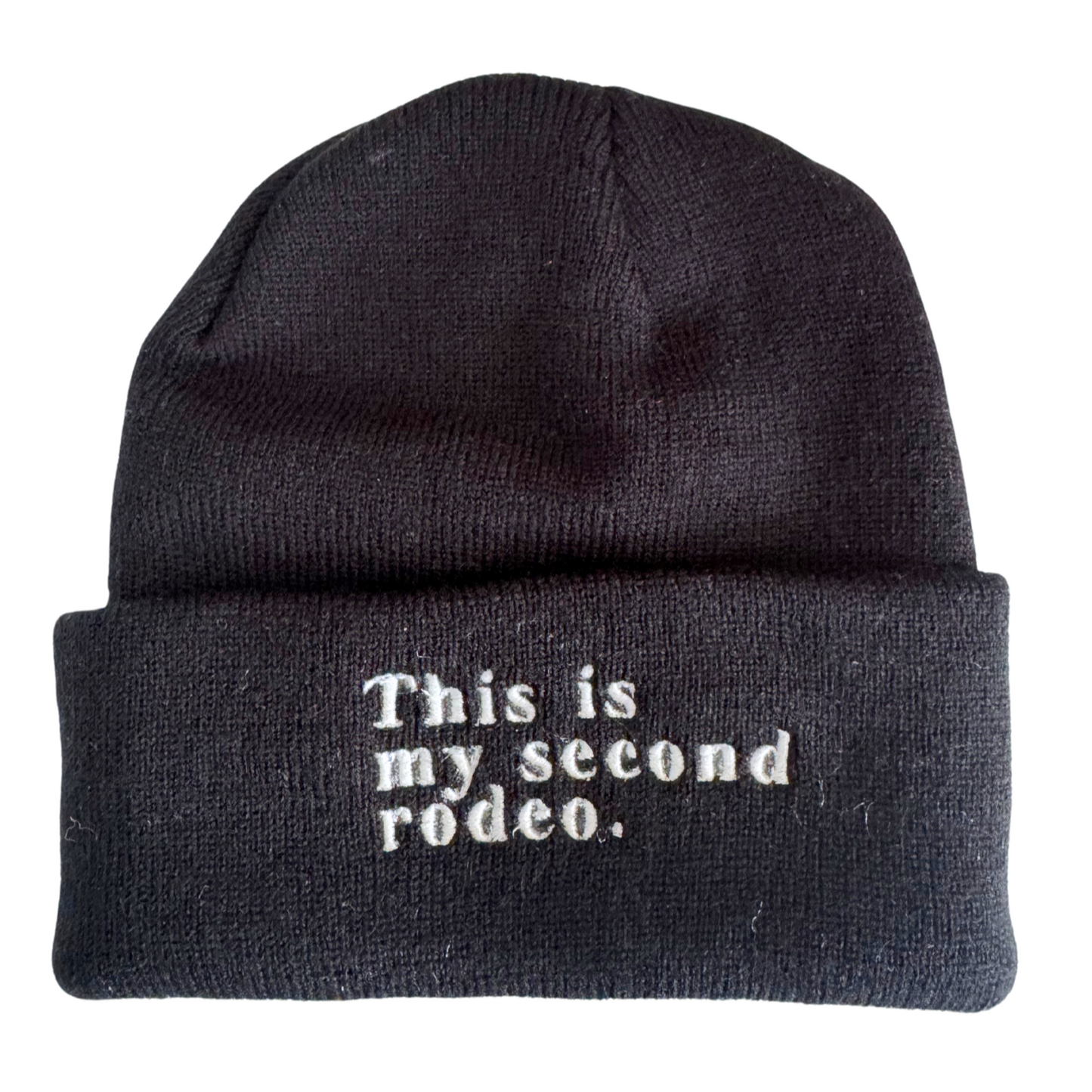 Black beanie with white embroidered text saying "This is my second rodeo."