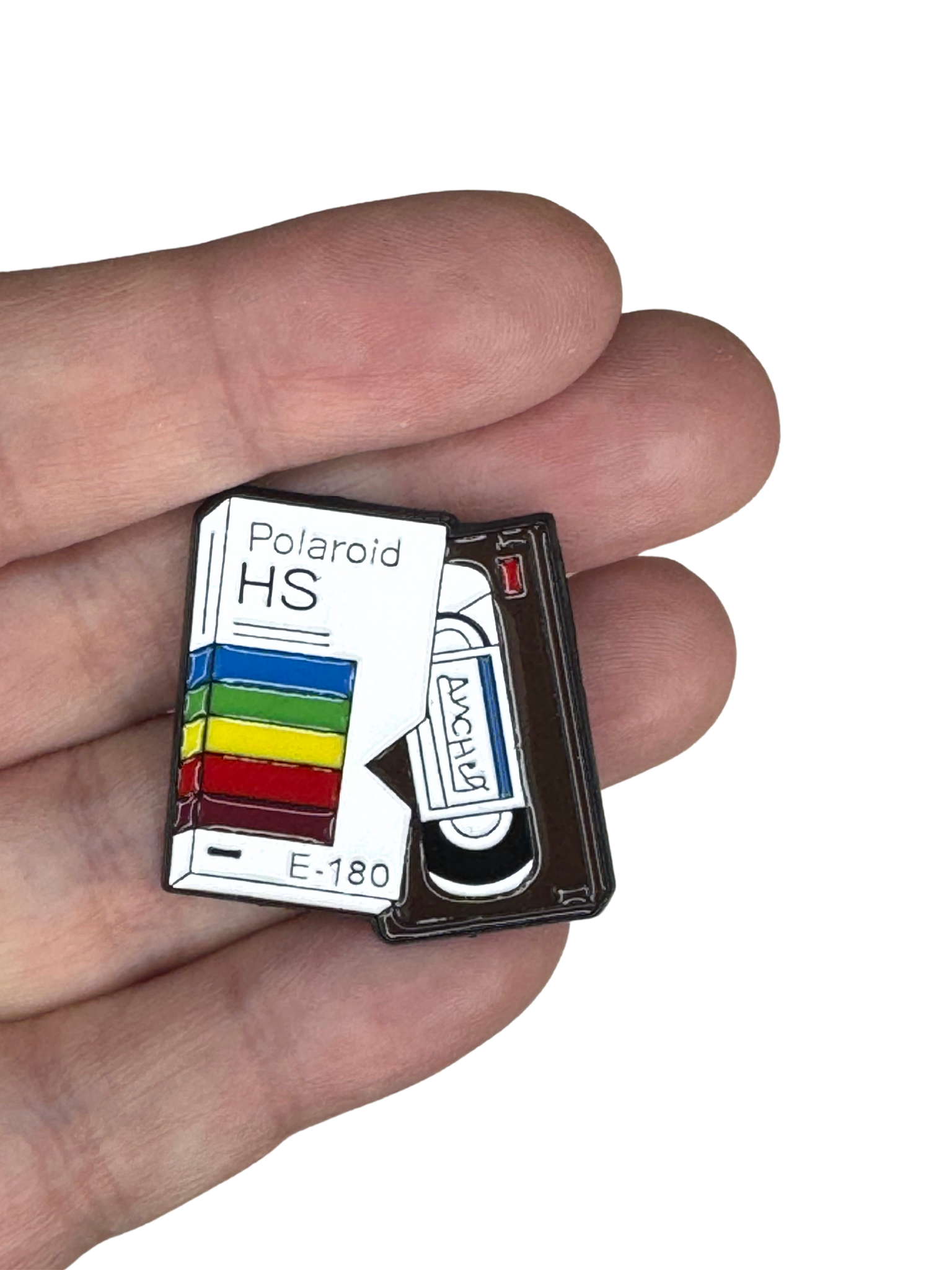 VHS enamel pin shown in hand for scale