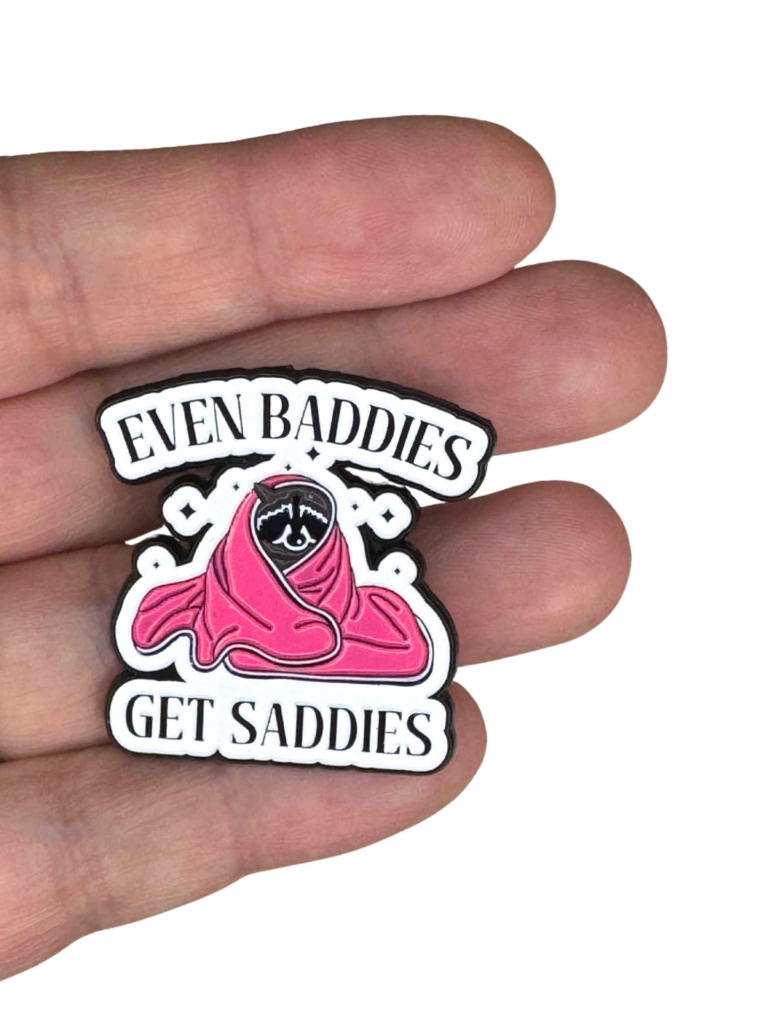 Even Baddies Get Saddies” enamel pin held between fingers to show size.