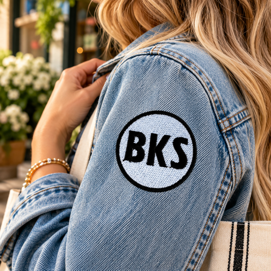 Black and white embroidered Brookside BKS patch on sleeve of light-wash denim jacket outdoors