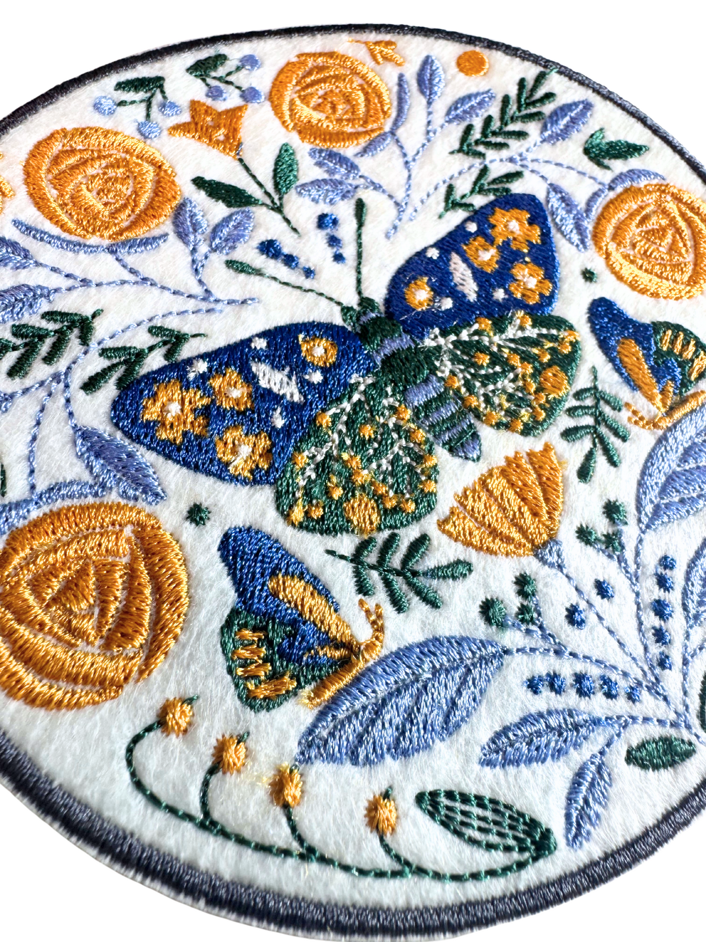 Close-up of embroidered floral butterfly patch showing stitching details and texture