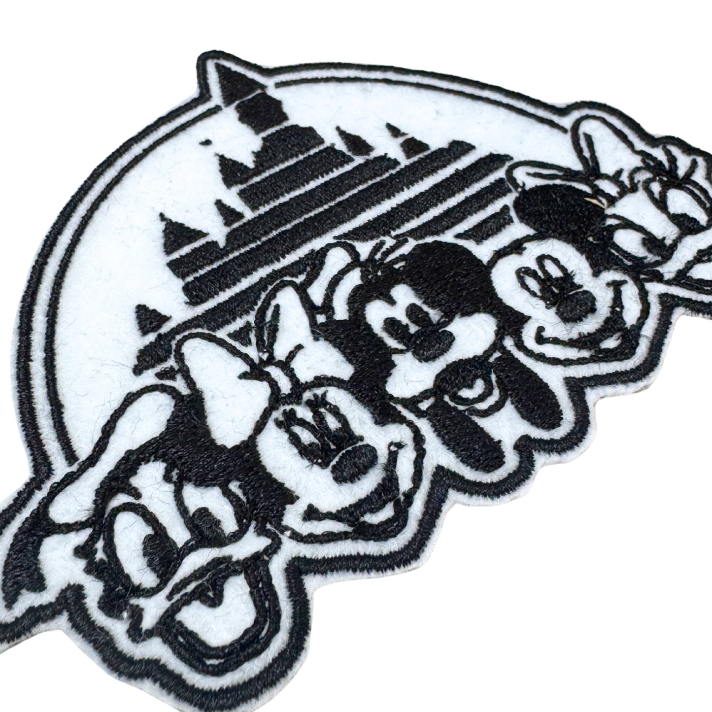 Close-up angled view of black and white castle and friends embroidered patch