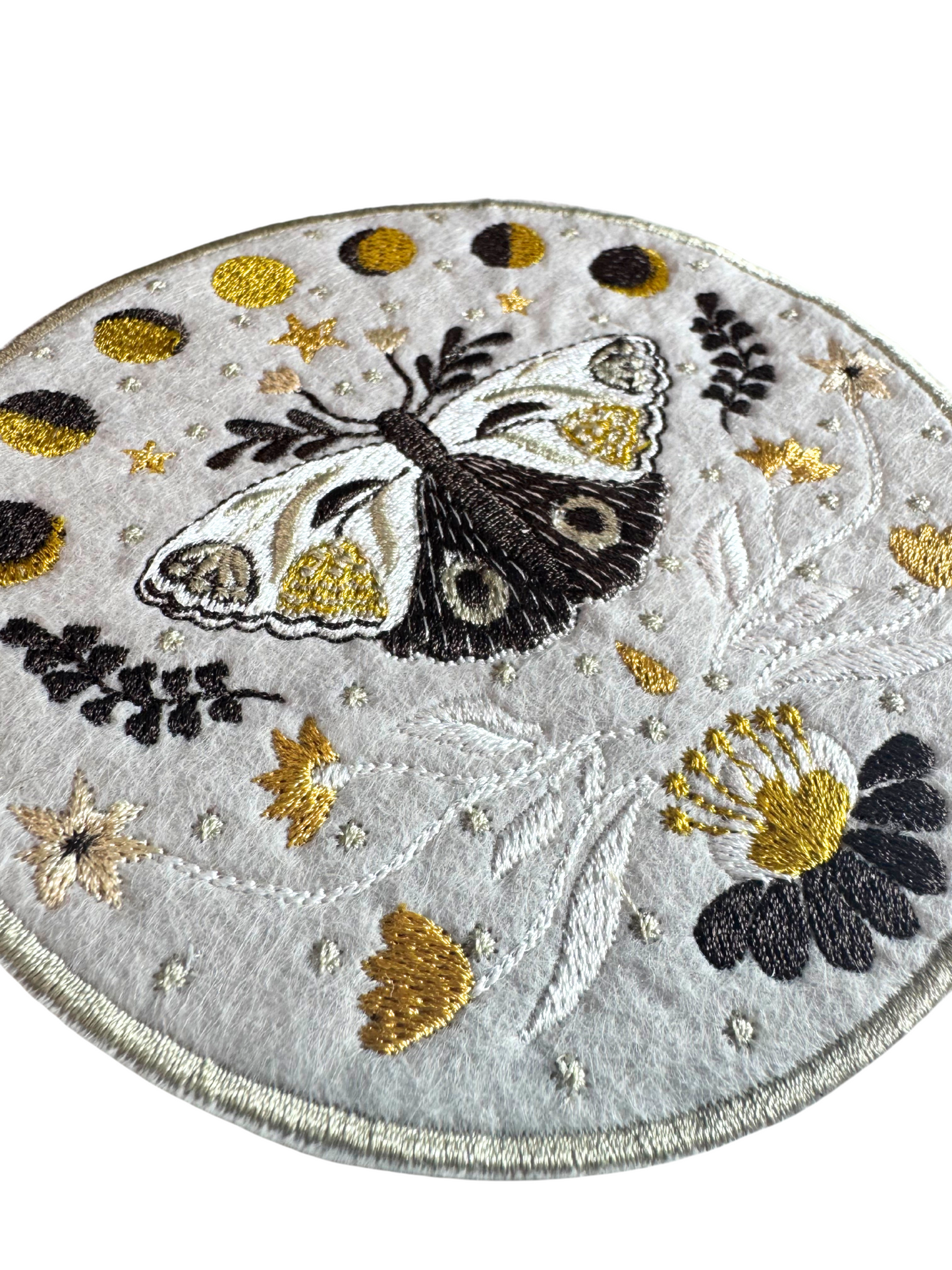 Close-up view of celestial moth patch showing moon phase embroidery and detailed stitching