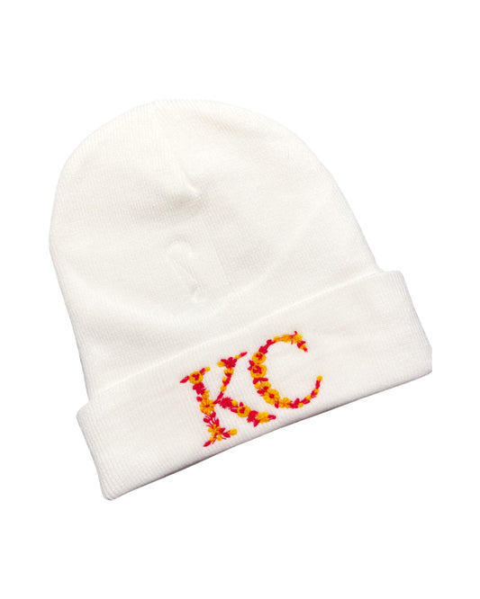 white acrylic beanie embroidered with the letters KC made of red and yellow kc chiefs colored flowers