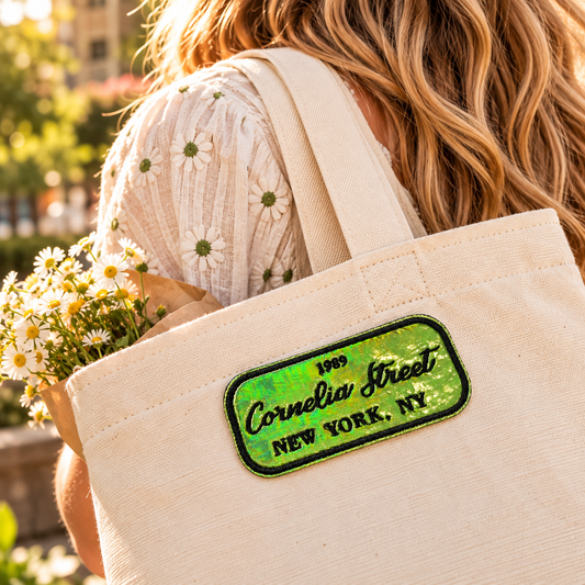 Green holographic Cornelia Street iron-on patch on a cream canvas tote carried outdoors