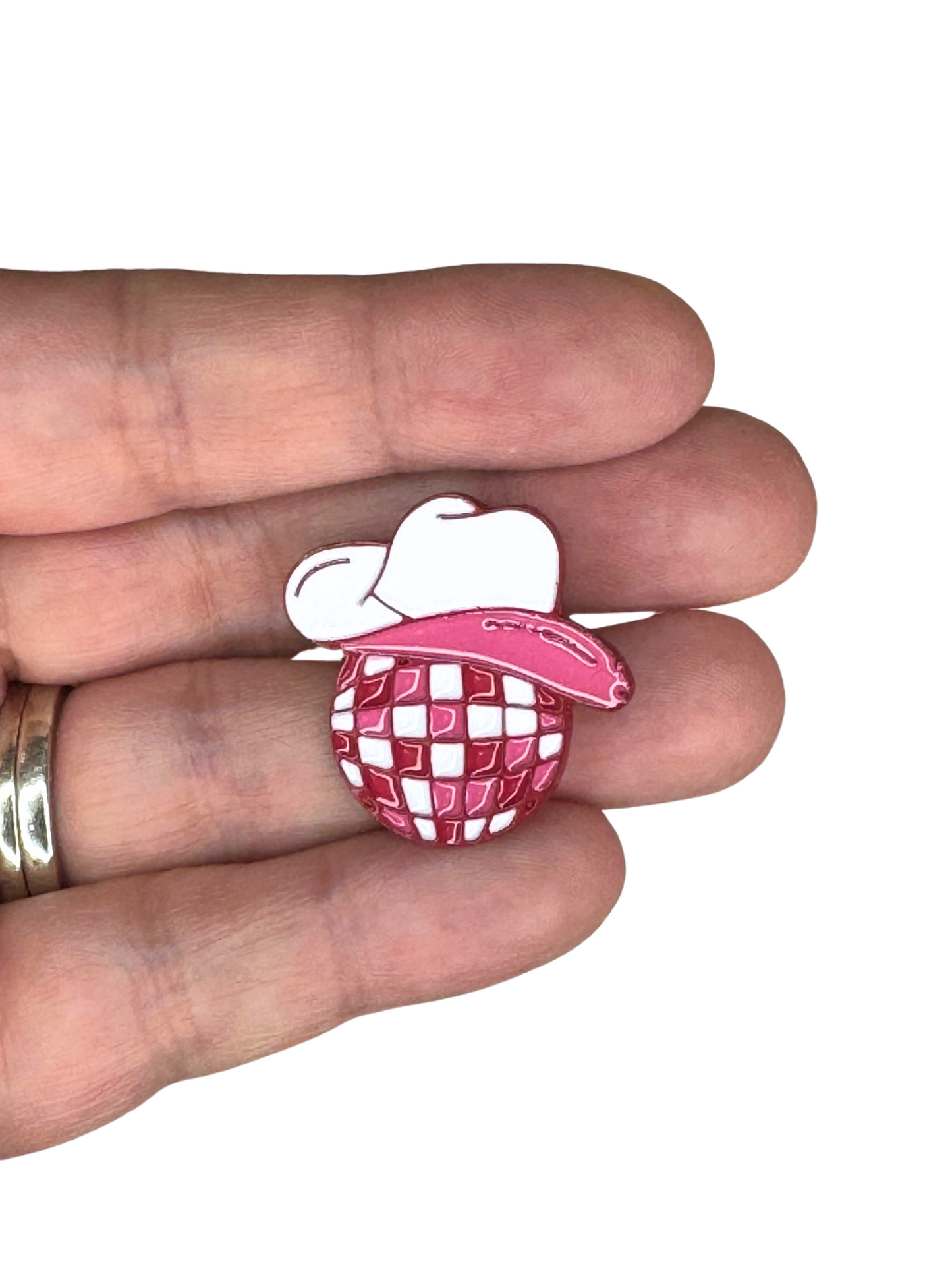 Cowgirl disco ball enamel pin held in hand for size reference