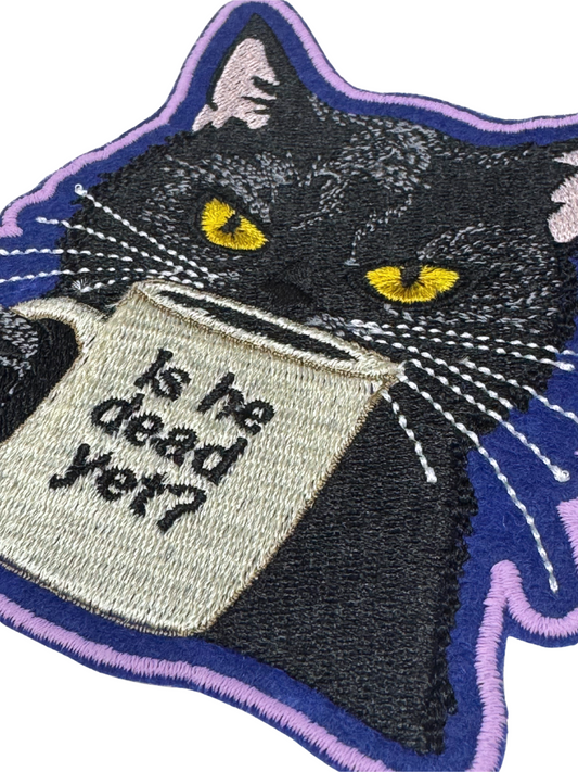 Close-up angled view of embroidered black cat coffee patch with purple border