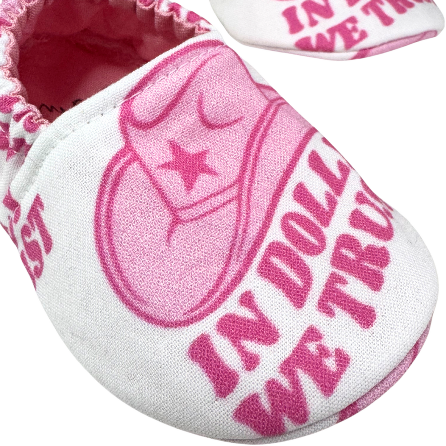 “Close-up of pink ‘In Dolly We Trust’ cowboy hat design on handmade baby moccasins, 3-6 months”