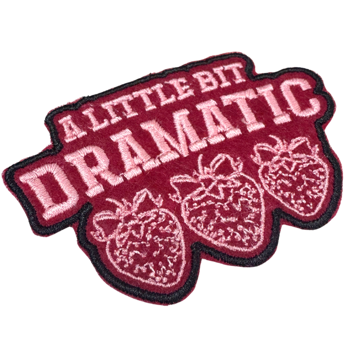 “angled closeup of embroidered strawberry patch with dramatic text”