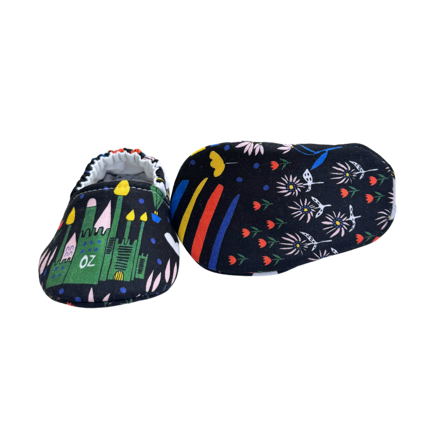 Bottom view of Emerald City baby moccasins, featuring a whimsical print with rainbows, flowers, and enchanted elements, designed for early foot development.