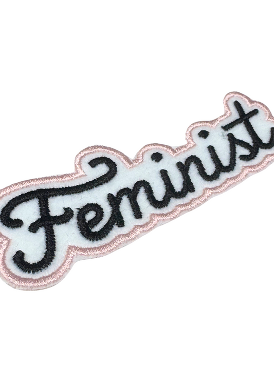 Angled close-up of embroidered feminist patch details