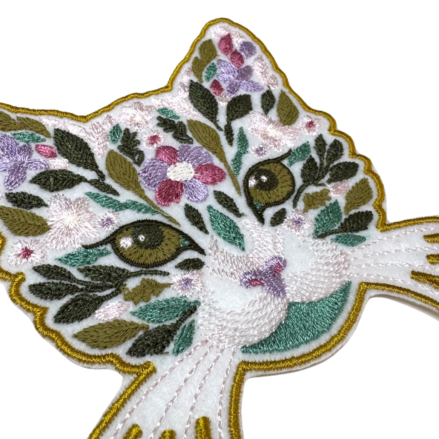 Close-up angled view of floral cat embroidered patch with pastel flowers