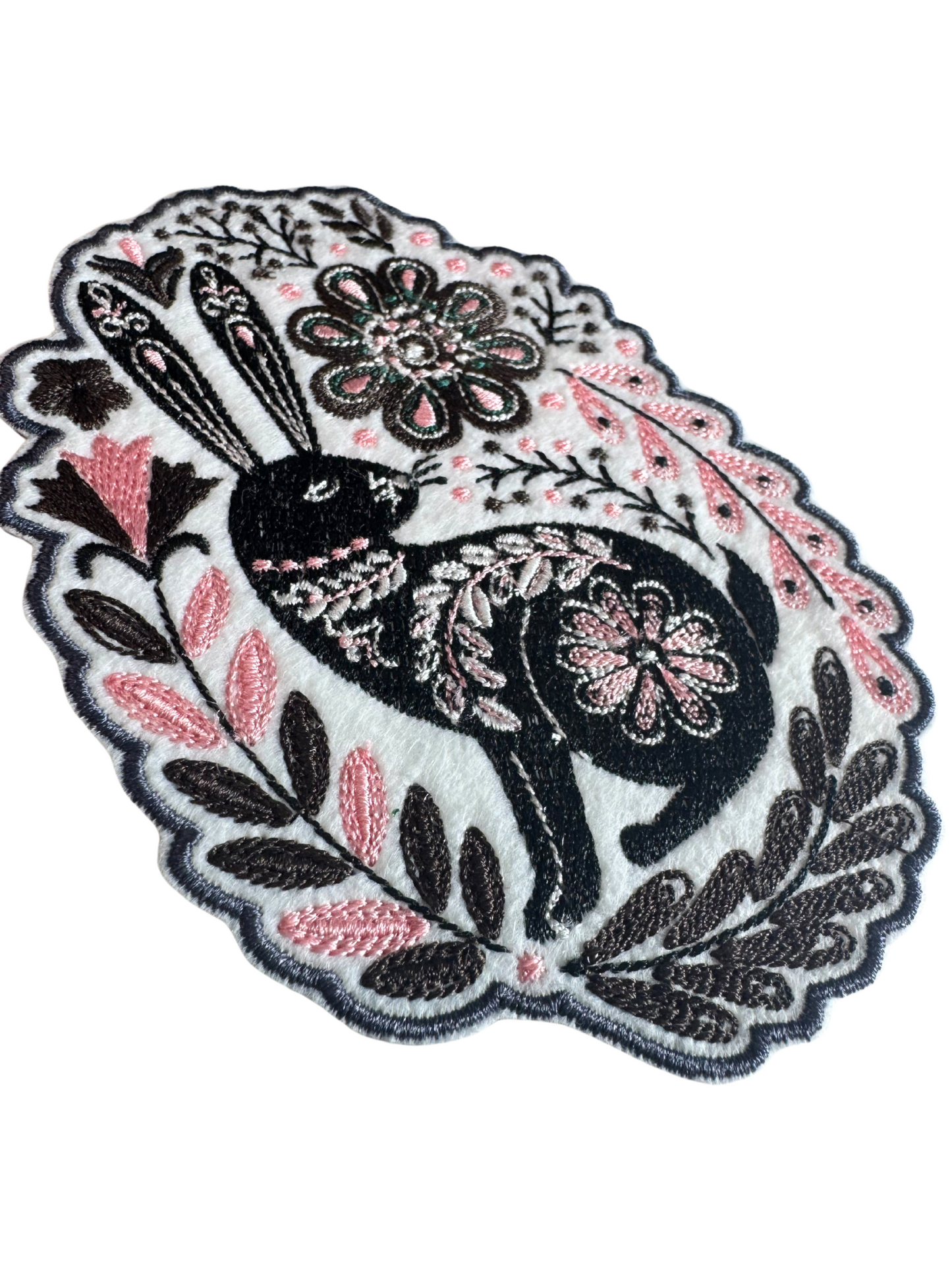Close-up of embroidered black bunny patch with pink floral detailing and textured stitching