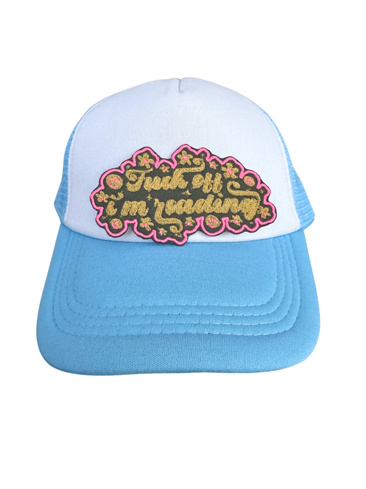 Blue and white trucker hat styled with the "Fuck Off I'm Reading" floral patch, handmade and bold.