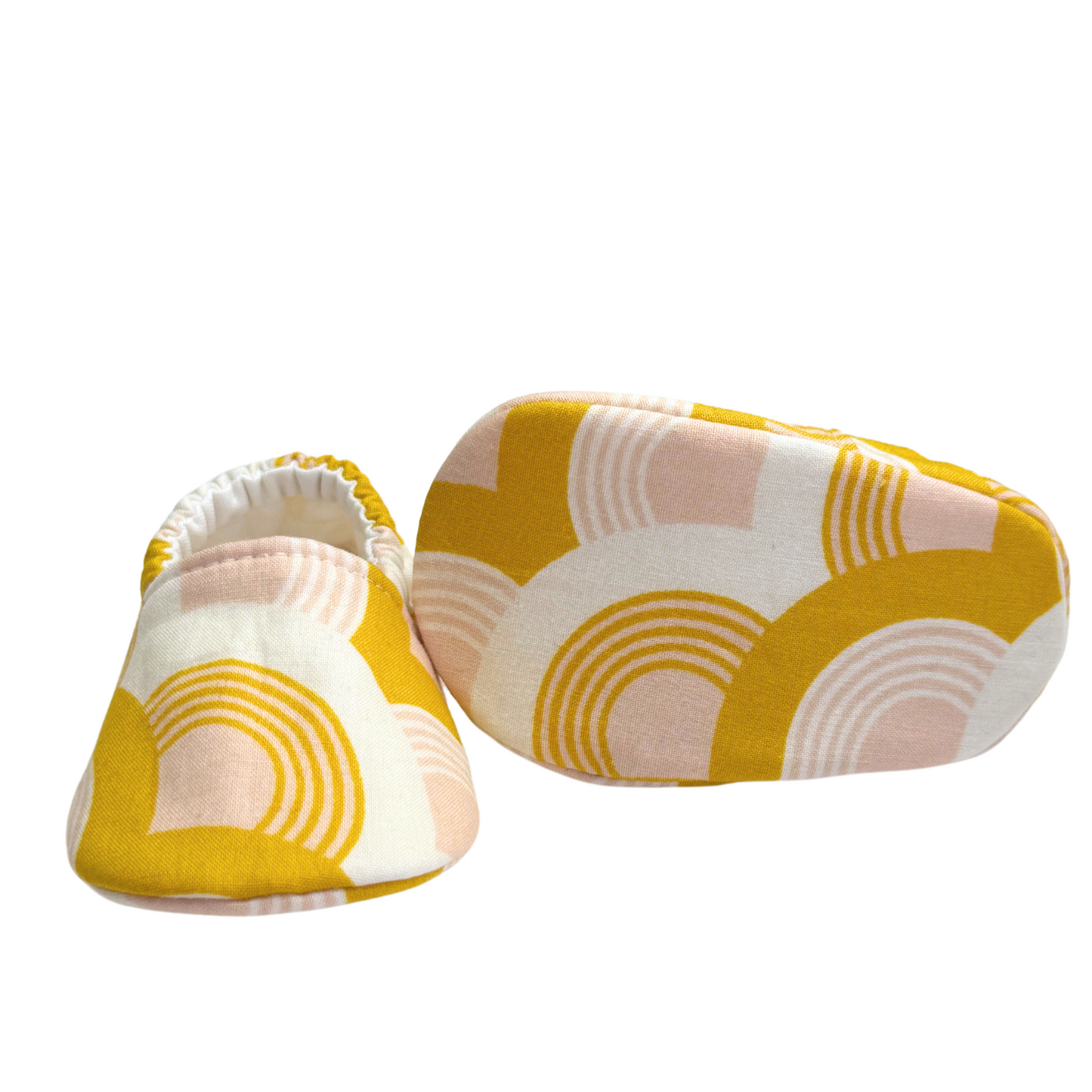 Bottom view of golden rainbow baby moccasins, highlighting the soft, flexible soles designed for early foot development and all-day comfort.