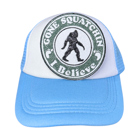 "Gone Squatchin' – I Believe" embroidered patch attached to a light blue and white trucker hat.
