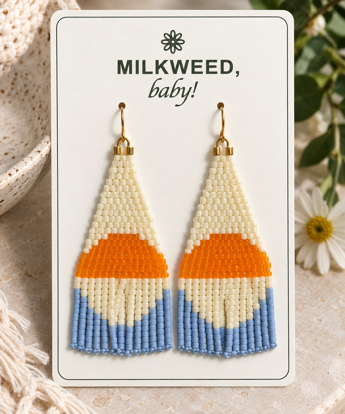 Hand-beaded ivory, orange and periwinkle fringe earrings on a Milkweed baby display card