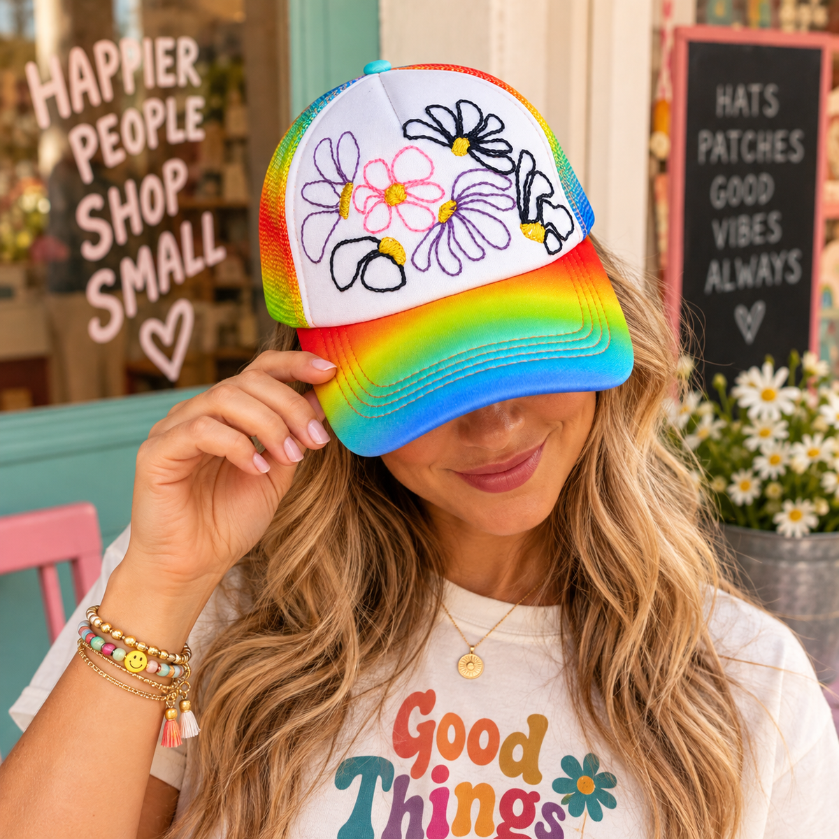 Model wearing hand-embroidered rainbow floral trucker hat