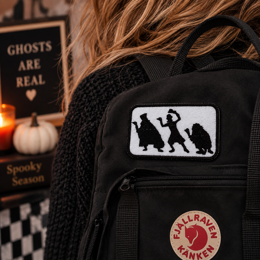 Hitchhiking Ghosts embroidered patch shown on a black backpack in a Halloween lifestyle setting.