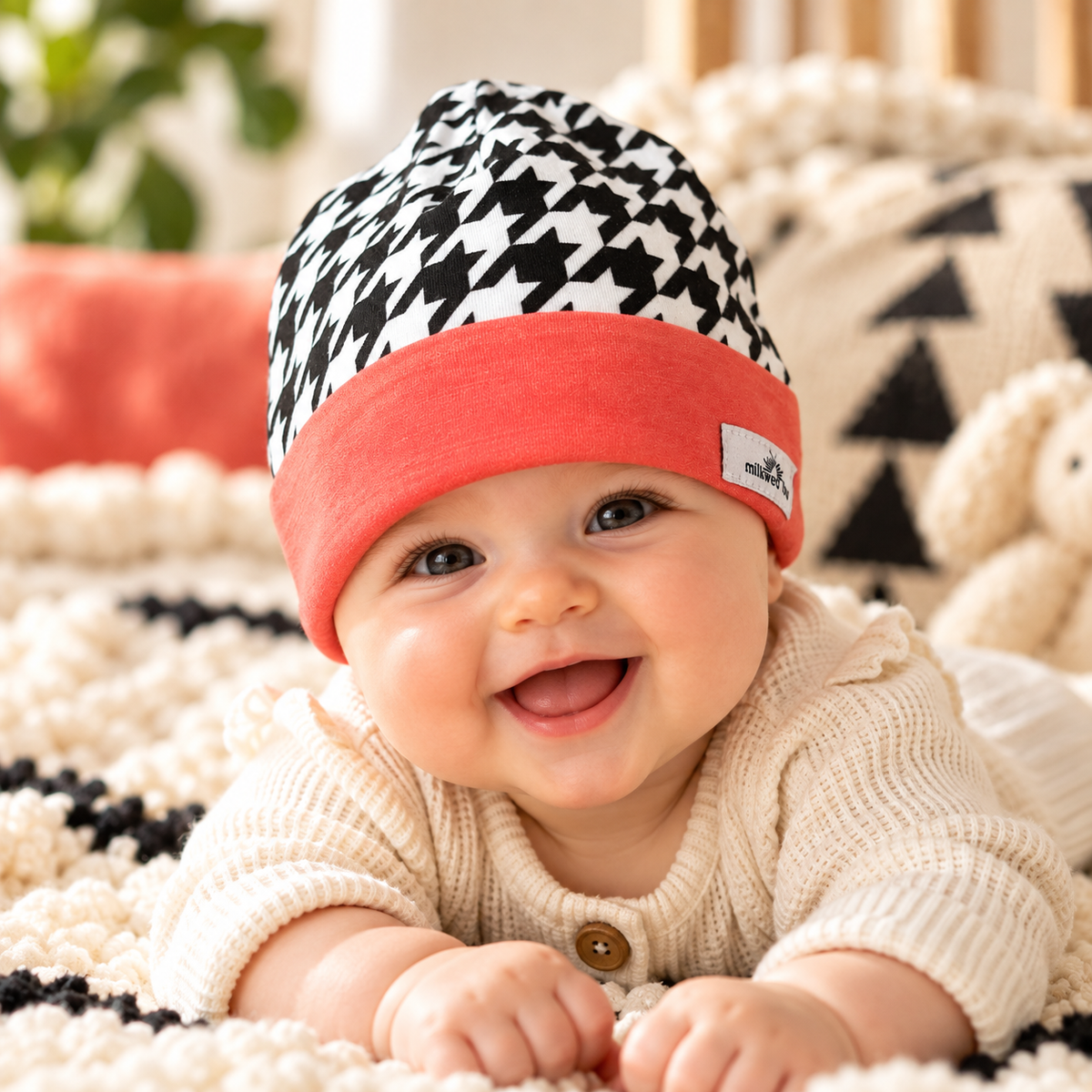 Baby wearing houndstooth and coral cuff beanie during supervised tummy time
