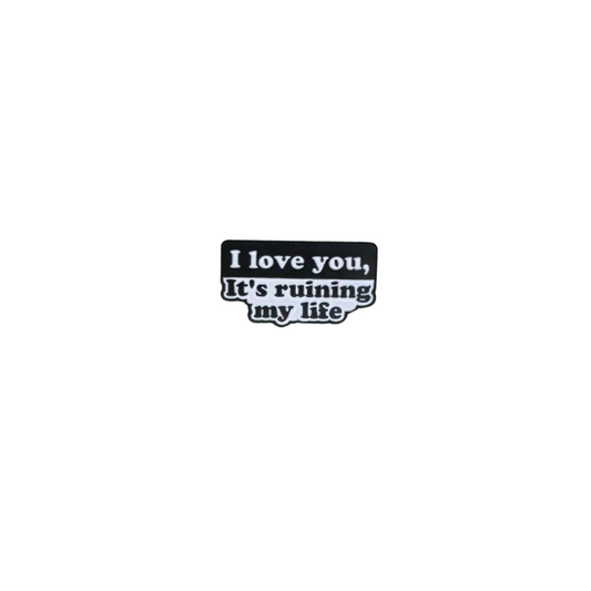 Enamel pin reading "I love you, it’s ruining my life" on a plain white background