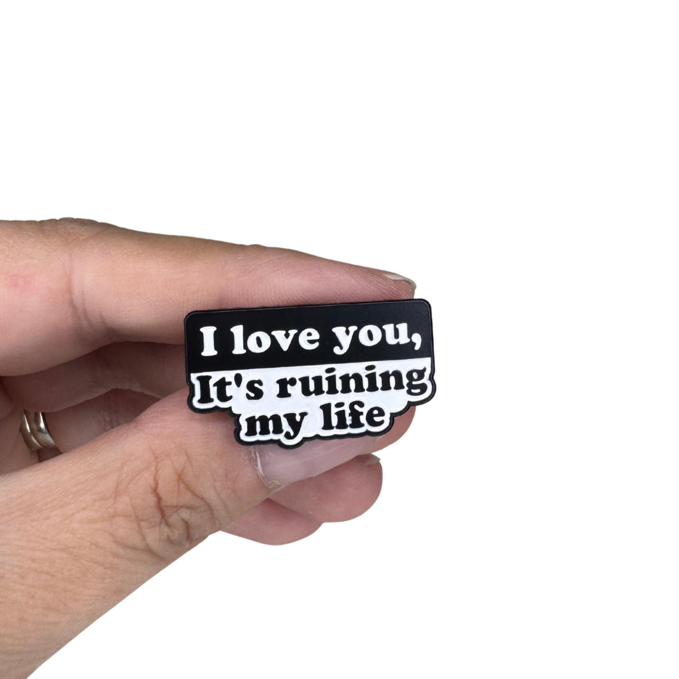 Enamel pin shown in hand for size reference