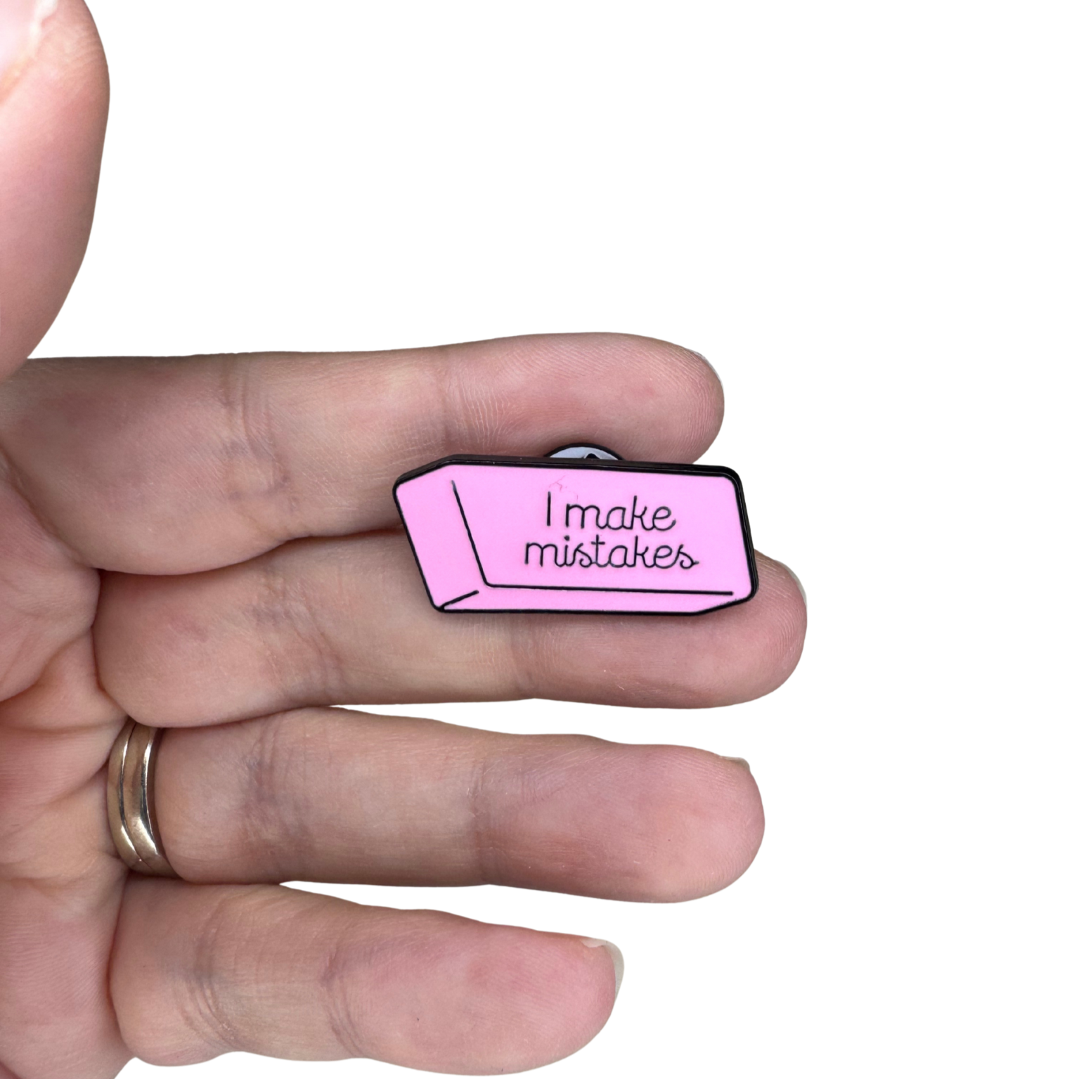 Hand holding pink enamel eraser pin for size reference