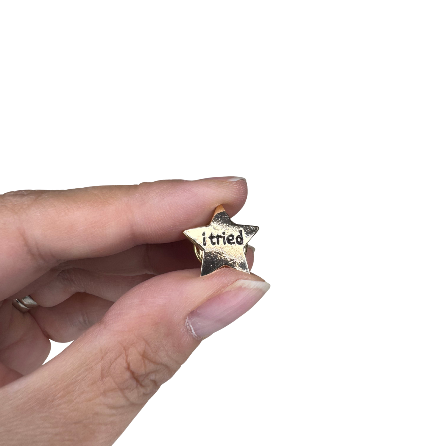 The pin held between two fingers to show scale