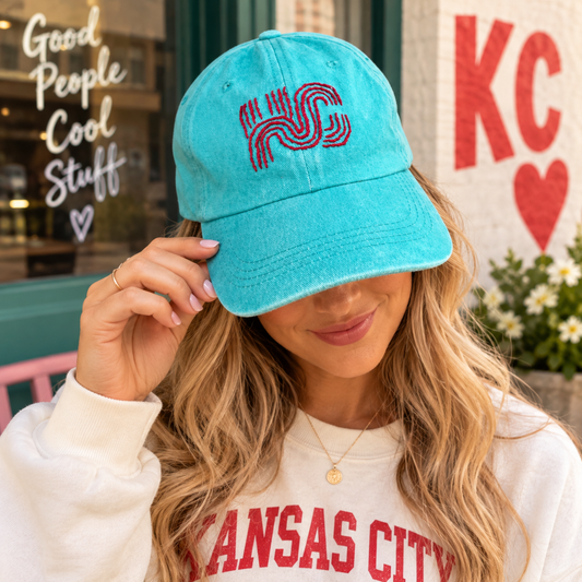 Model wearing hand-embroidered KC Current turquoise baseball hat