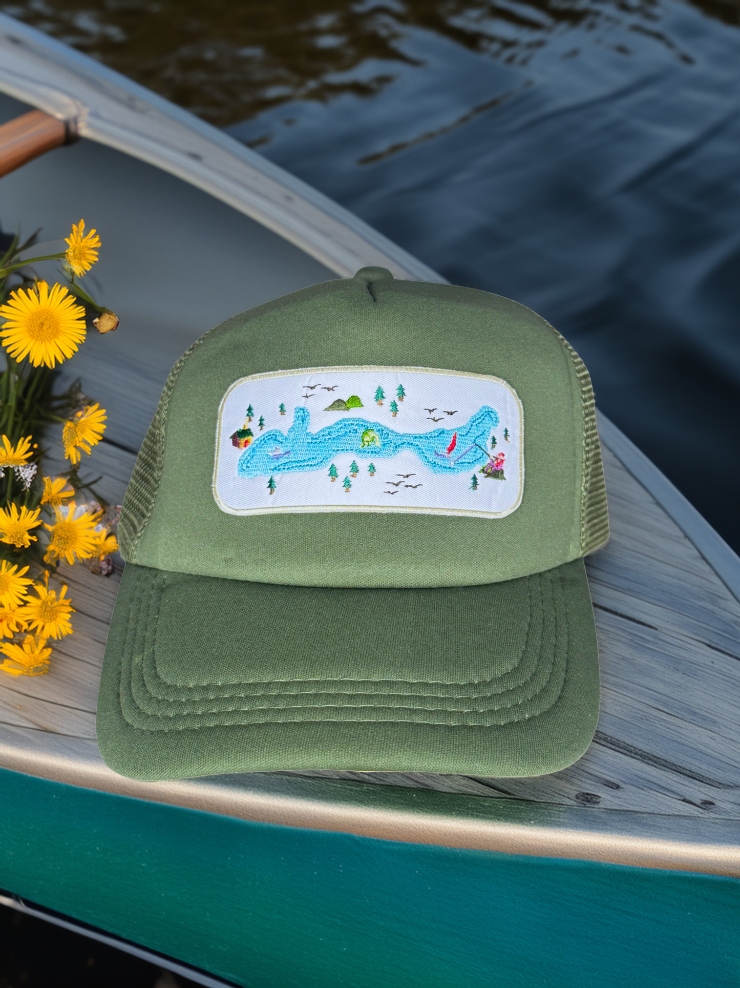 Green cap with a scenic patch on a canoe with yellow flowers