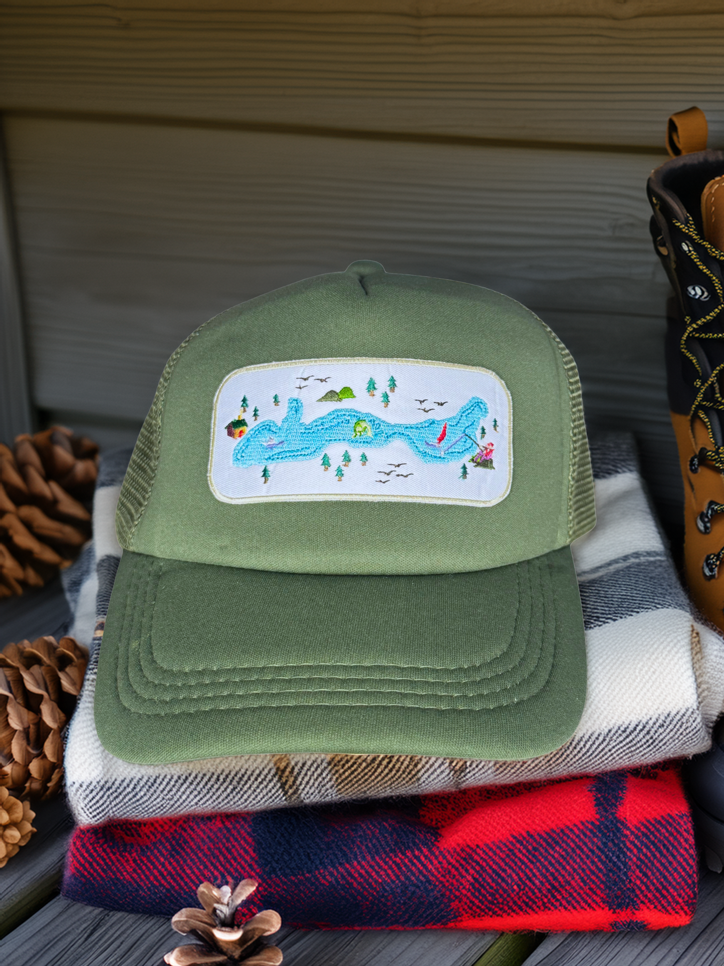 Green trucker hat with a colorful patch on a stack of plaid fabrics.