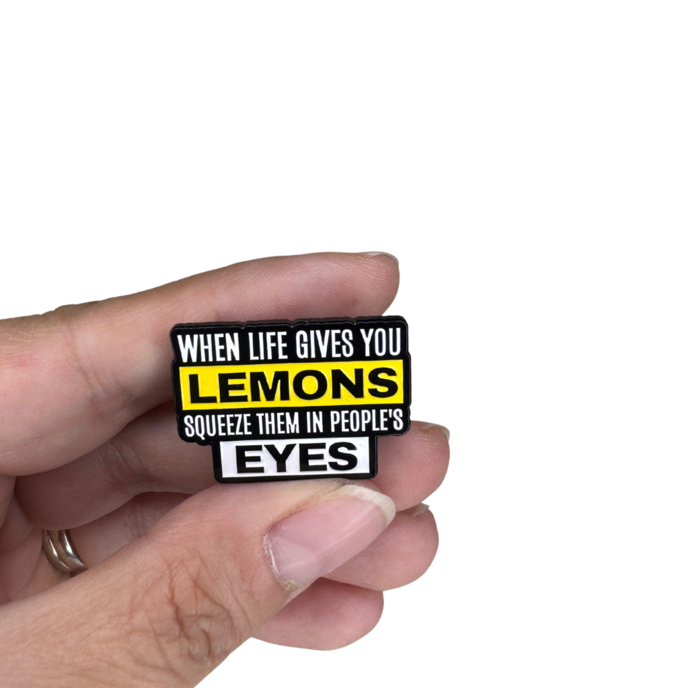 “Lemons” enamel pin held in hand for scale