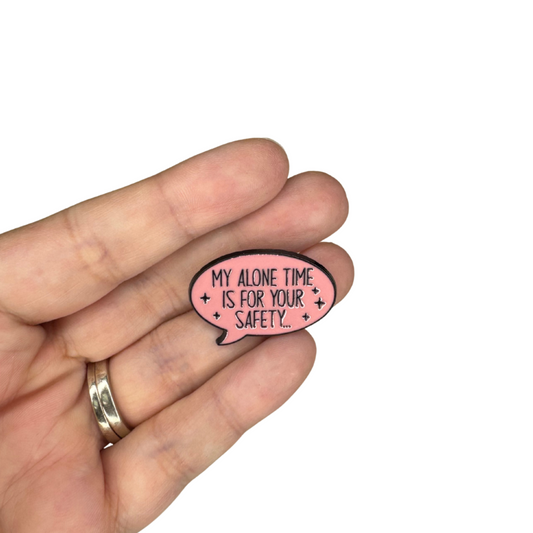 Hand holding “My Alone Time Is For Your Safety” pink enamel pin for size reference