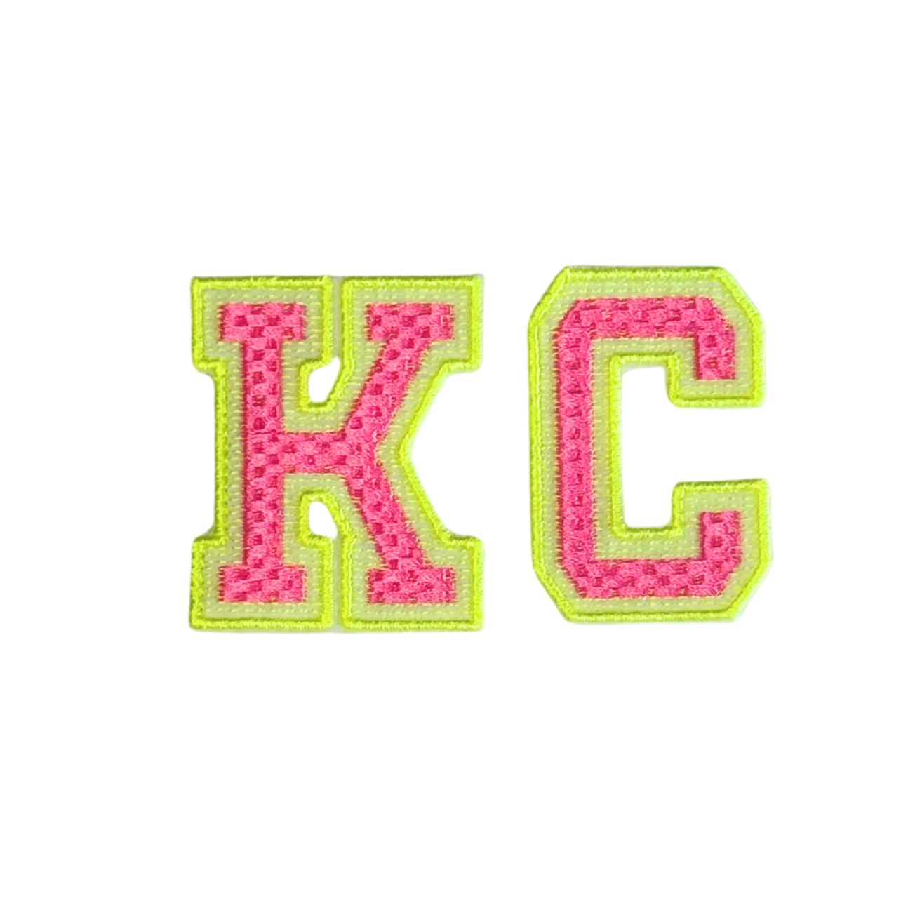 Embroidered patch that says “KC” in neon pink and yellow varsity-style letters