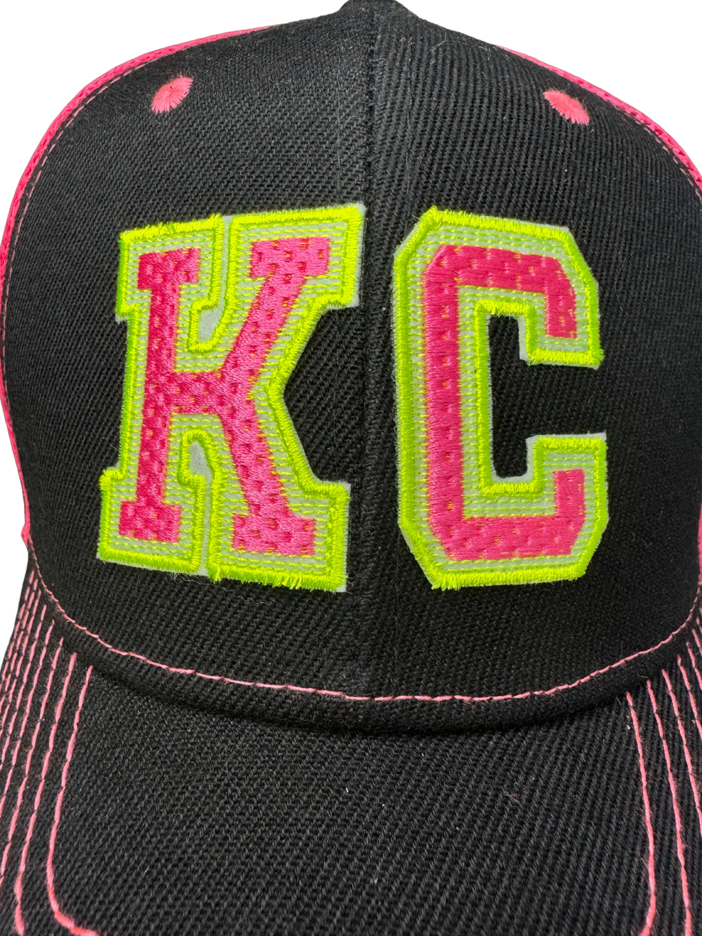 Closeup of KC patch embroidered in neon pink and yellow on black trucker hat
