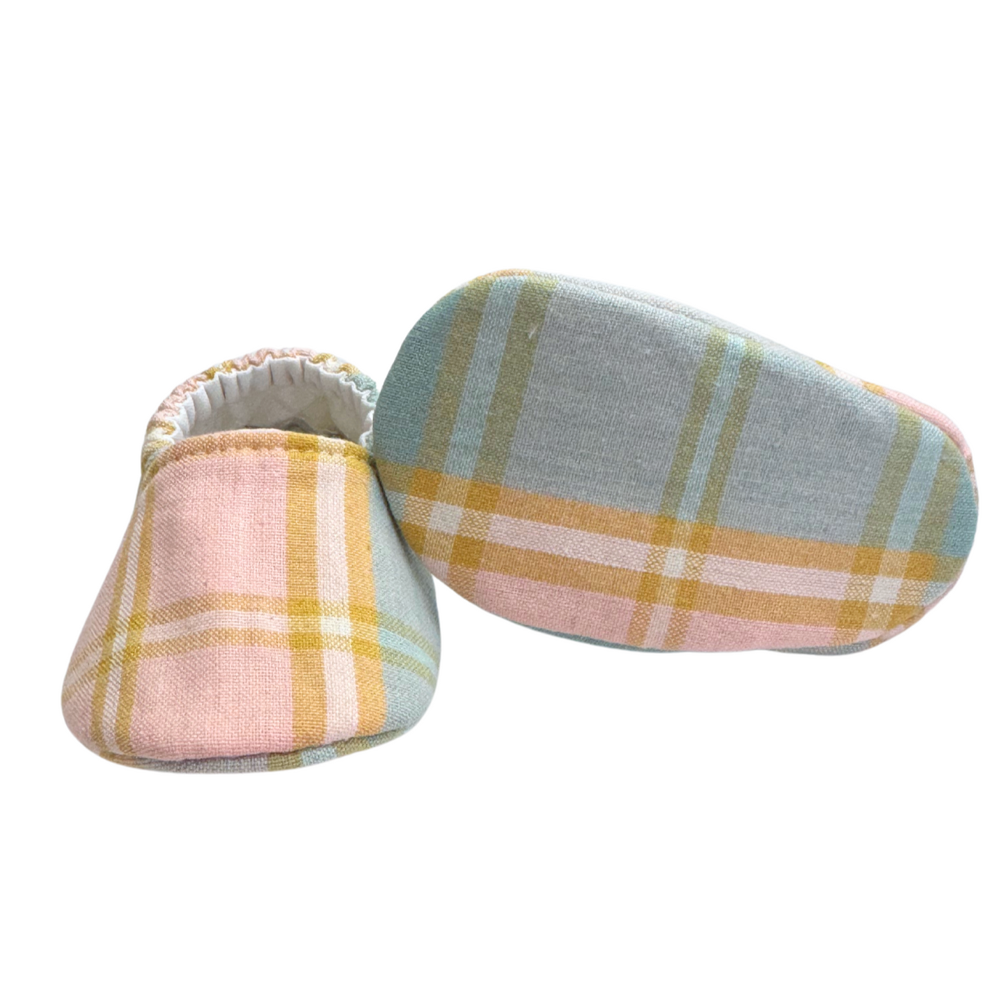 Bottom view of pastel plaid baby moccasins, highlighting the soft, flexible sole designed for newborn foot development and all-day comfort.