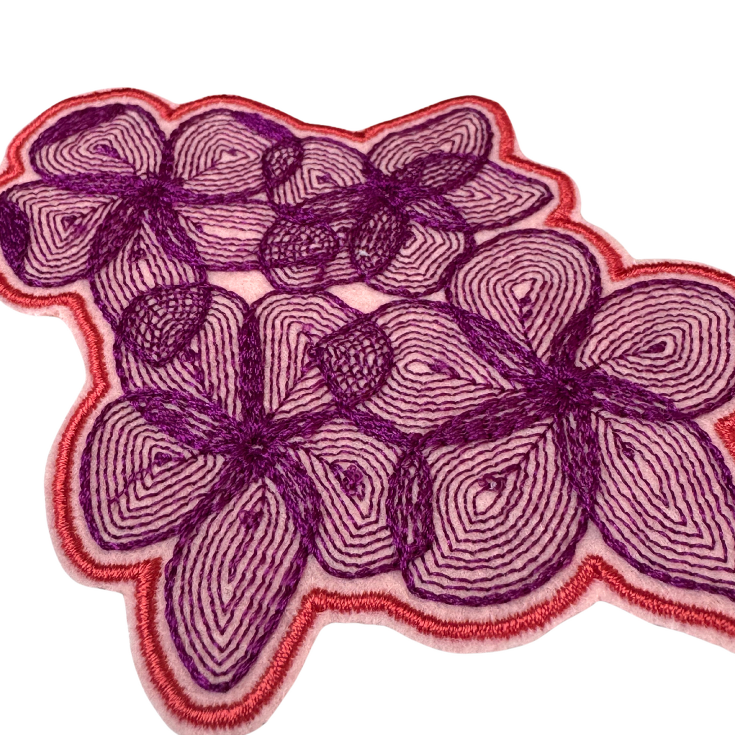 Close-up angled view of pink and purple floral embroidered patch
