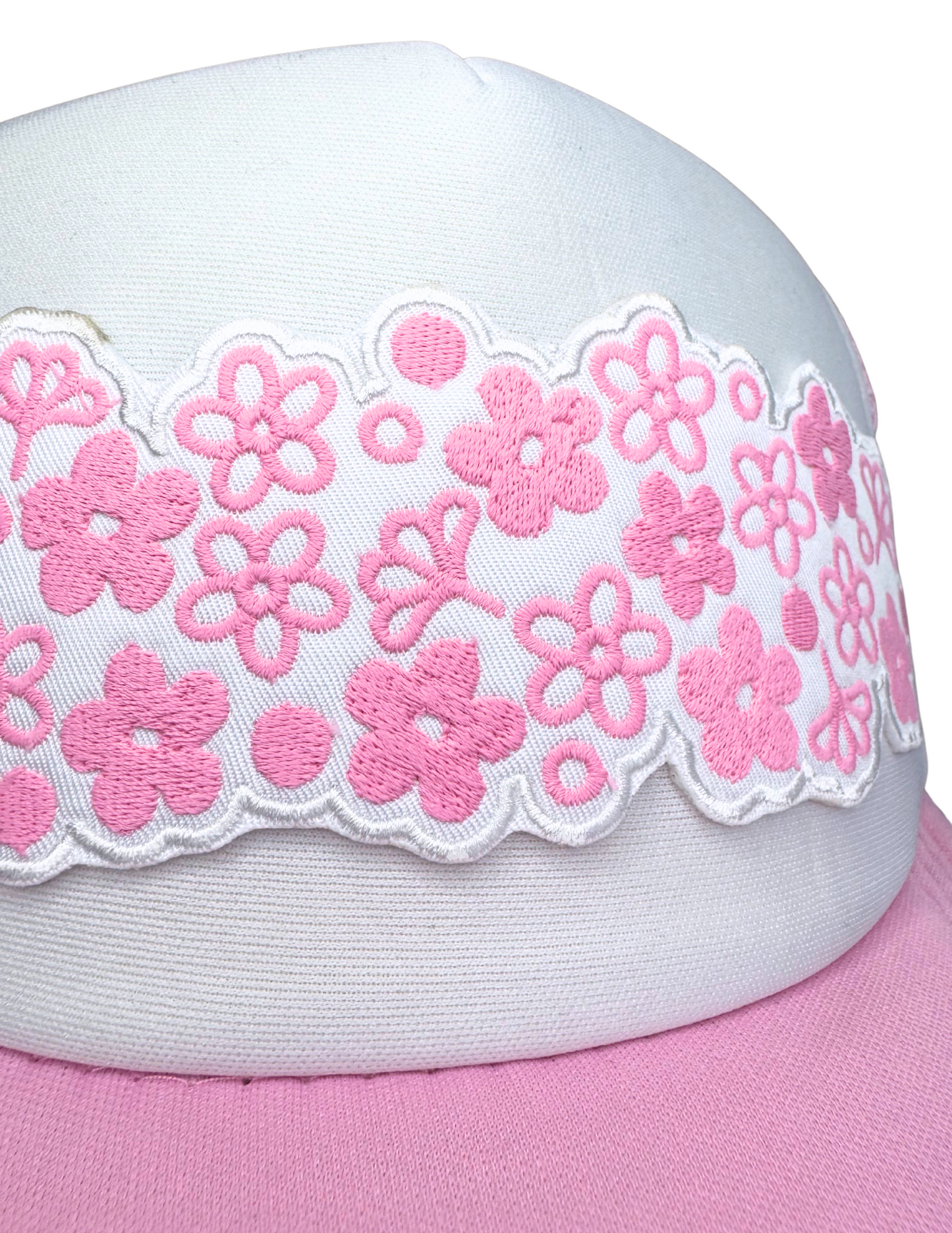 Closeup of pink floral embroidery on scalloped white patch in Spring Blossom design on trucker hat